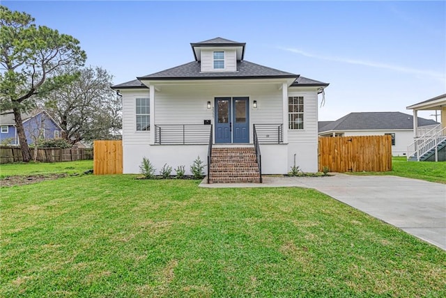 bungalow-style house featuring covered porch, fence, and a front lawn