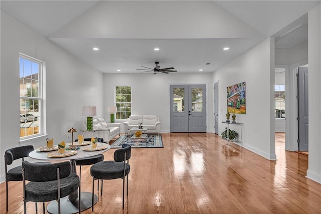 living area featuring baseboards, vaulted ceiling, french doors, light wood-style floors, and recessed lighting