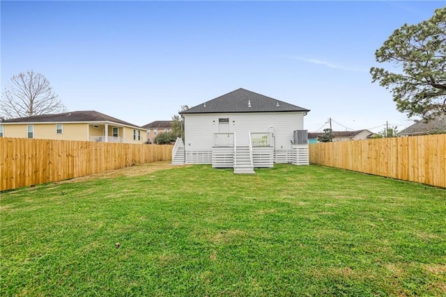 rear view of property featuring cooling unit, a fenced backyard, and a lawn