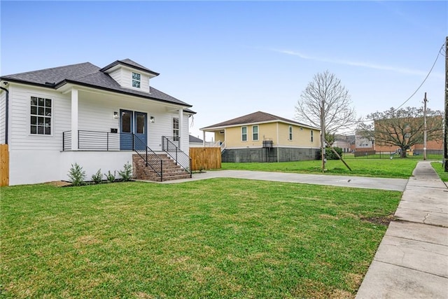 bungalow-style home featuring a shingled roof, a front yard, and fence