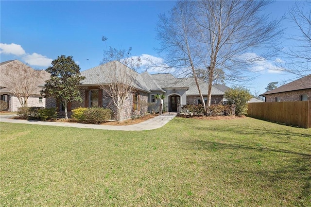 single story home featuring brick siding, fence, and a front yard