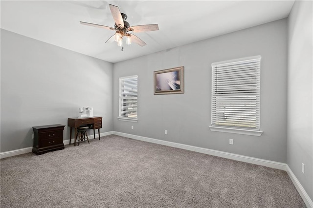 carpeted empty room with ceiling fan and baseboards