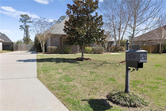 view of front of house with brick siding, fence, a front lawn, and roof with shingles