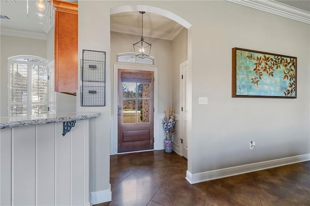 entryway featuring baseboards, arched walkways, crown molding, and dark tile patterned flooring