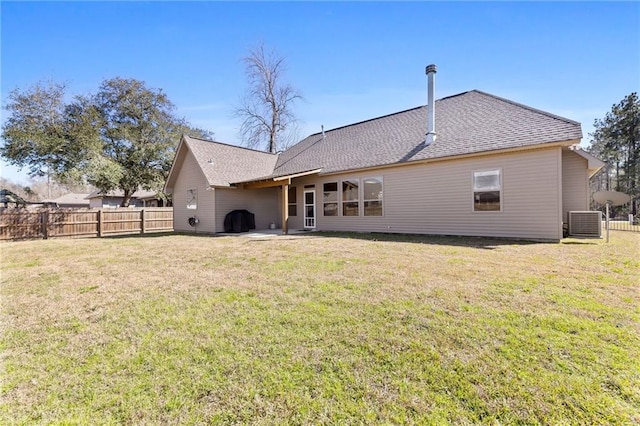 back of property featuring roof with shingles, fence, and a yard