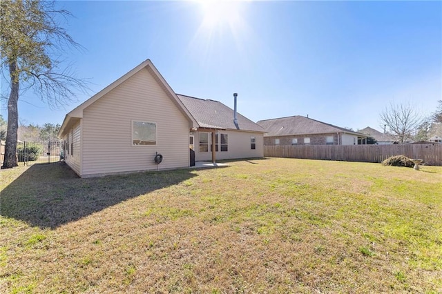 rear view of house with a fenced backyard and a lawn