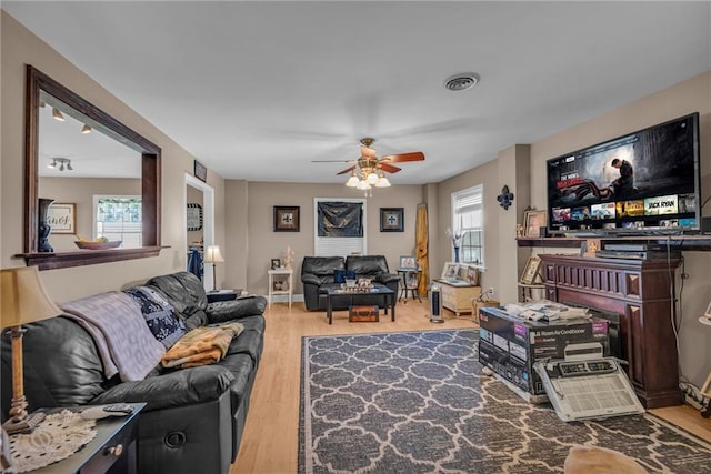 living area with a ceiling fan, baseboards, visible vents, and wood finished floors