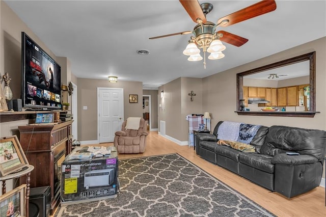 living room with baseboards, visible vents, ceiling fan, and wood finished floors