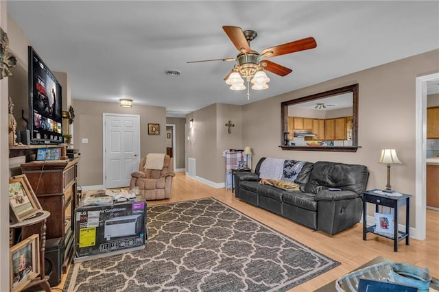 living room with visible vents, ceiling fan, baseboards, and wood finished floors