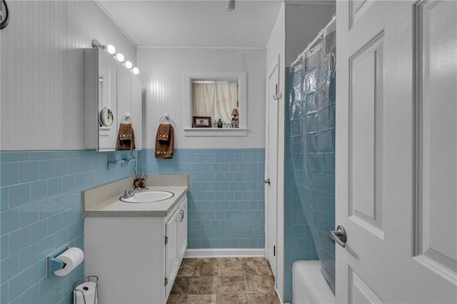 full bath with tile walls, wainscoting, and vanity