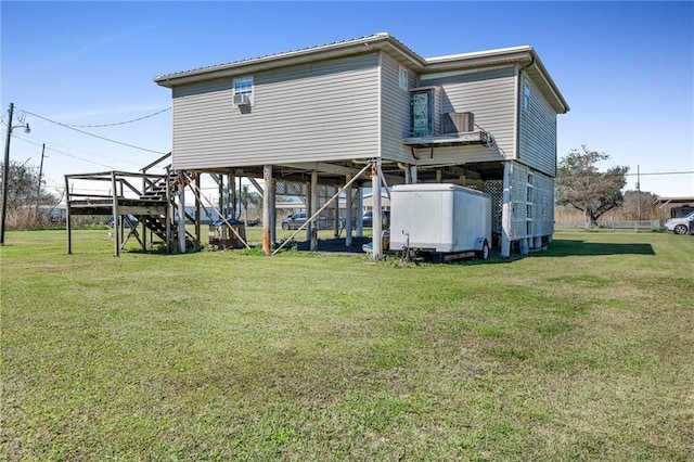 rear view of house with a lawn and stairs