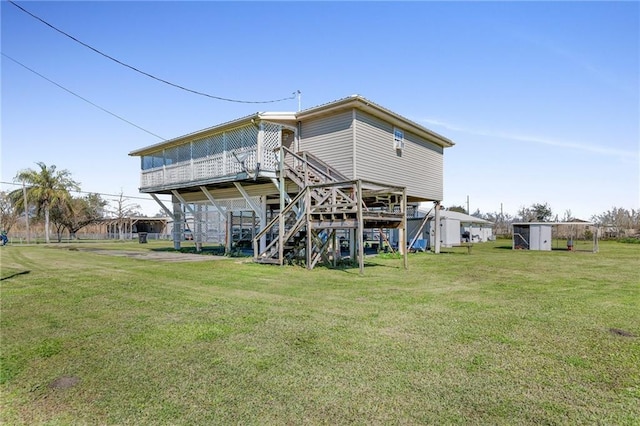 rear view of property featuring a yard, a storage unit, stairway, and an outdoor structure