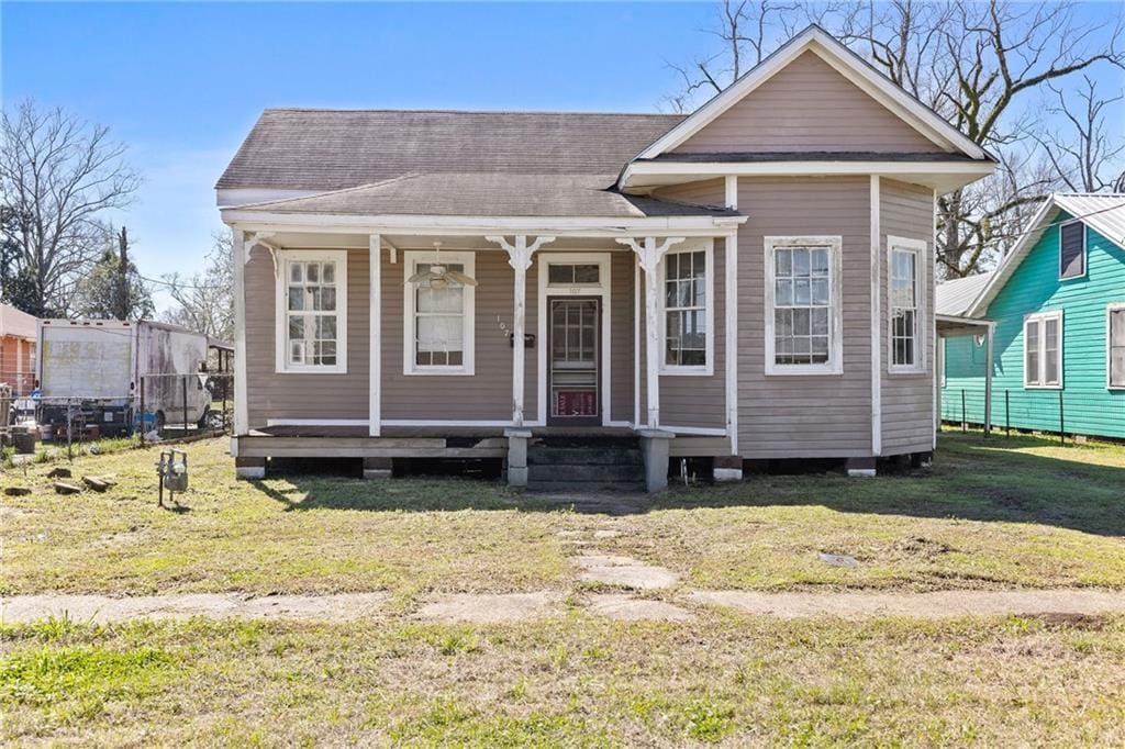 view of front of house with a porch, a front yard, and roof with shingles