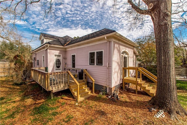 rear view of house featuring fence and a wooden deck