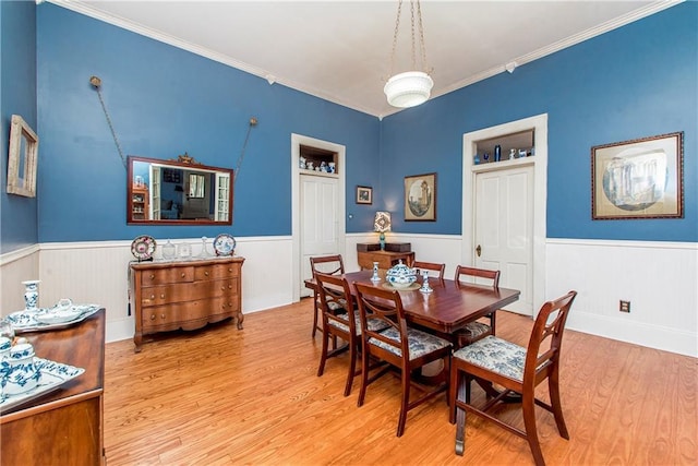 dining room with wainscoting, wood finished floors, and crown molding