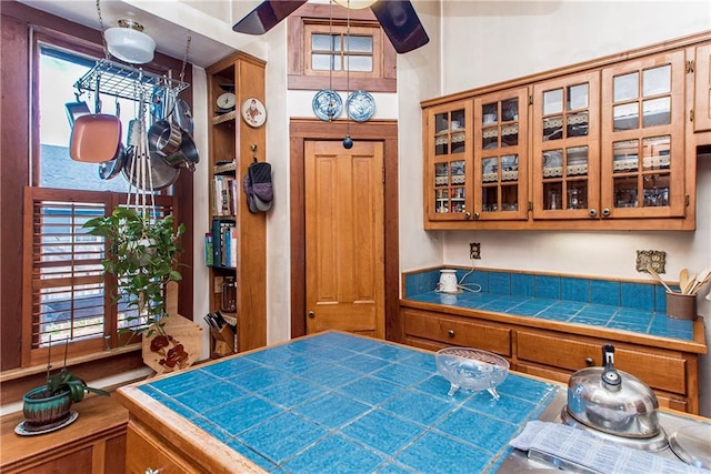 interior space featuring glass insert cabinets, brown cabinets, and tile counters