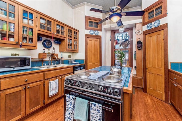 kitchen featuring stainless steel microwave, brown cabinets, a sink, and range with electric stovetop