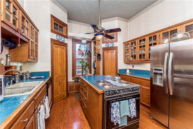 kitchen with electric range, brown cabinets, a sink, and stainless steel fridge with ice dispenser