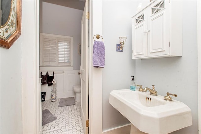 bathroom featuring toilet, tile patterned flooring, and a sink