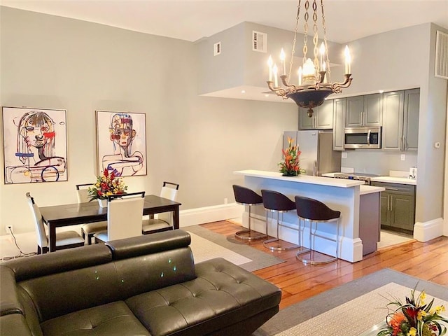 kitchen featuring stainless steel appliances, a kitchen breakfast bar, light wood-style floors, light countertops, and gray cabinets