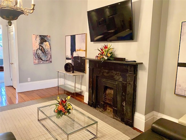 living room featuring a fireplace with flush hearth, baseboards, and hardwood / wood-style flooring