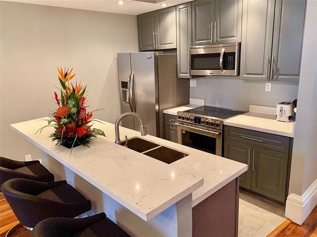 kitchen featuring appliances with stainless steel finishes, recessed lighting, a sink, and a kitchen breakfast bar