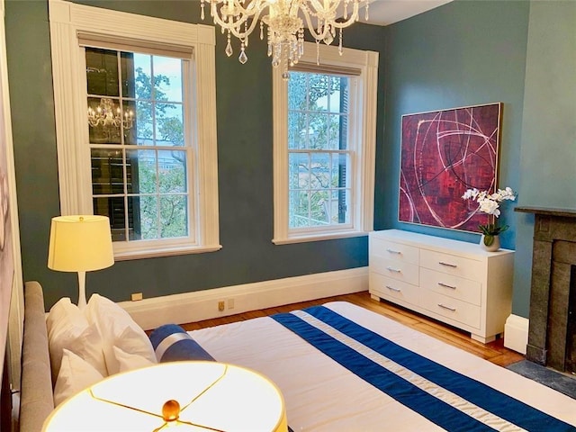 sitting room with an inviting chandelier, a fireplace with flush hearth, baseboards, and wood finished floors