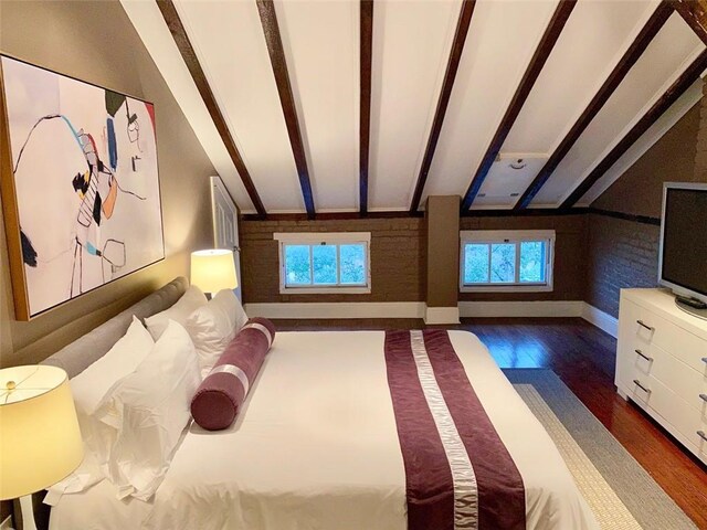 unfurnished bedroom featuring multiple windows, lofted ceiling with beams, baseboards, and wood finished floors