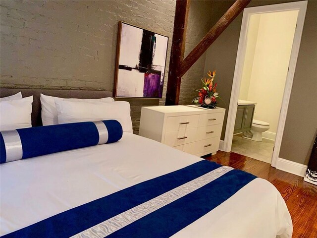 bedroom featuring ensuite bath, wood finished floors, and baseboards