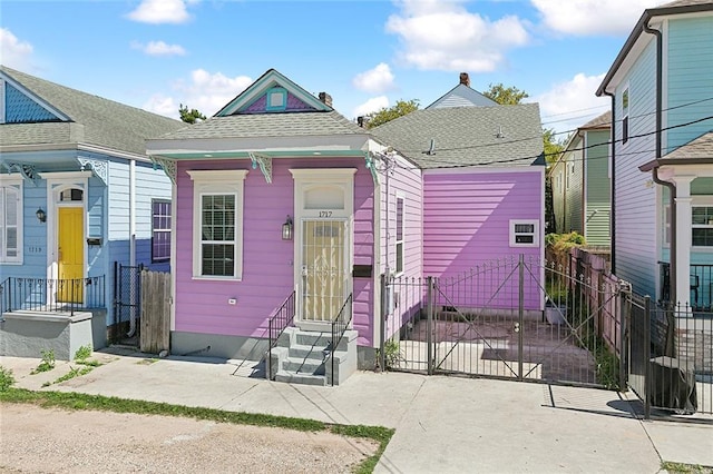 shotgun-style home with entry steps, fence, and roof with shingles