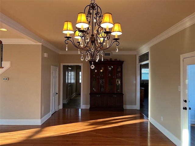 unfurnished dining area featuring baseboards, visible vents, ornamental molding, and wood finished floors