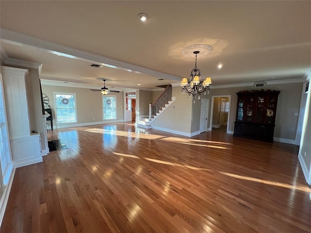 unfurnished living room with wood finished floors, visible vents, baseboards, stairs, and ornamental molding