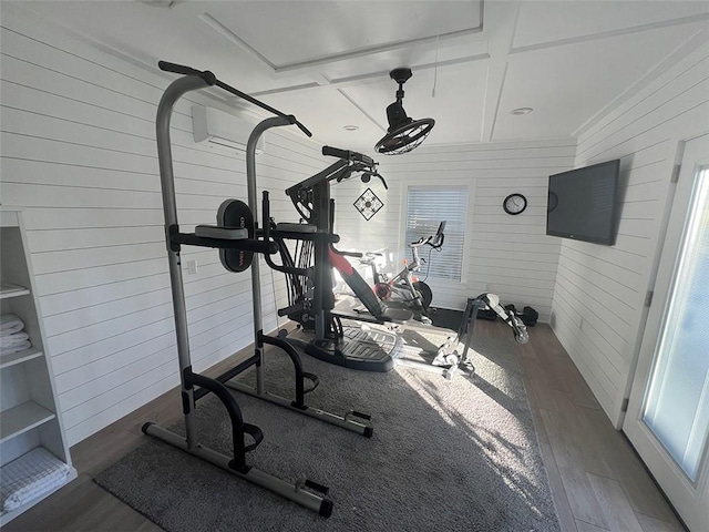 workout area featuring wood walls and wood finished floors