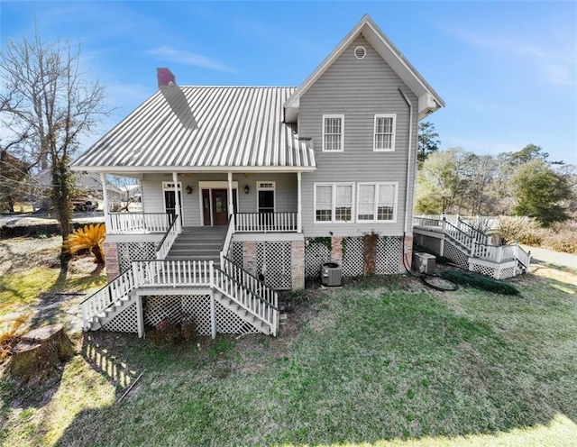 back of house featuring a chimney, stairway, a porch, and a yard