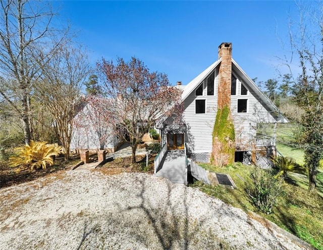 view of side of home featuring driveway and a chimney