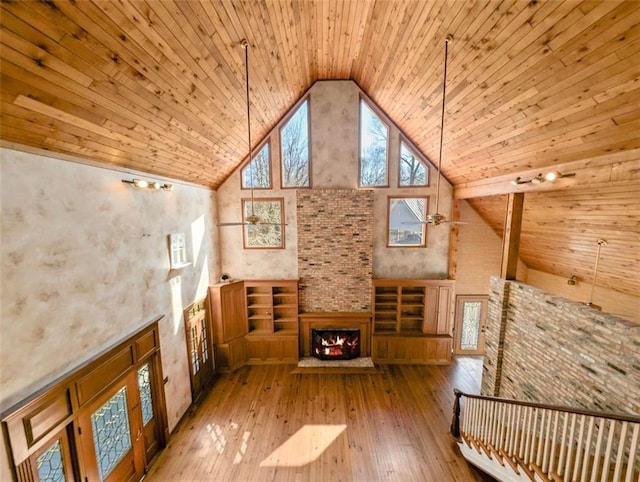 unfurnished living room featuring high vaulted ceiling, hardwood / wood-style floors, a multi sided fireplace, and wood ceiling