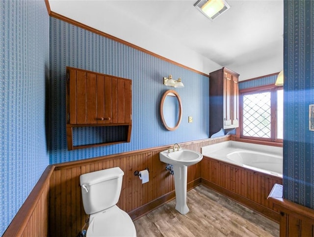 full bath with wallpapered walls, visible vents, toilet, a wainscoted wall, and wood finished floors