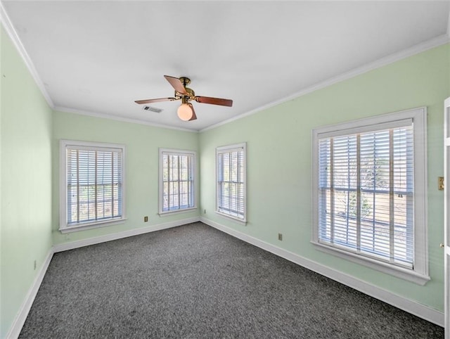 empty room featuring dark colored carpet, ornamental molding, visible vents, and baseboards