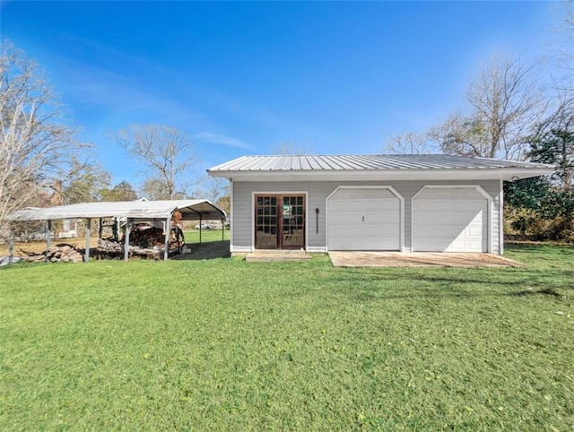 exterior space featuring metal roof, a yard, and a detached garage