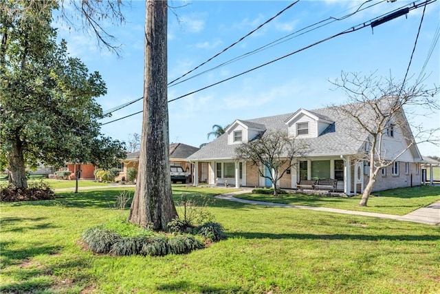 new england style home with a front yard, a porch, and brick siding