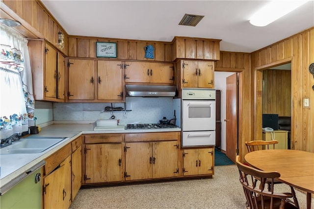 kitchen featuring a warming drawer, under cabinet range hood, a sink, dishwasher, and stainless steel gas cooktop