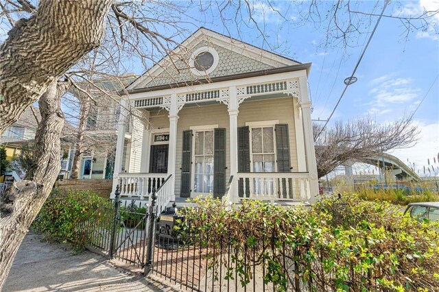 view of front of property featuring a fenced front yard, a gate, and a porch