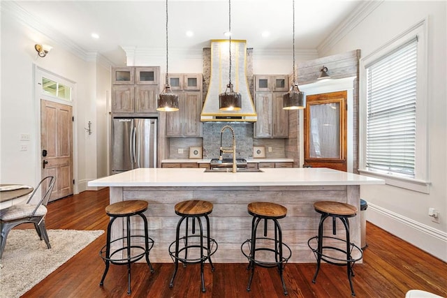 1244 Annunciation St, New Orleans, LA 70130 - kitchen featuring light countertops, custom range hood, decorative backsplash, freestanding refrigerator, and a kitchen island with sink