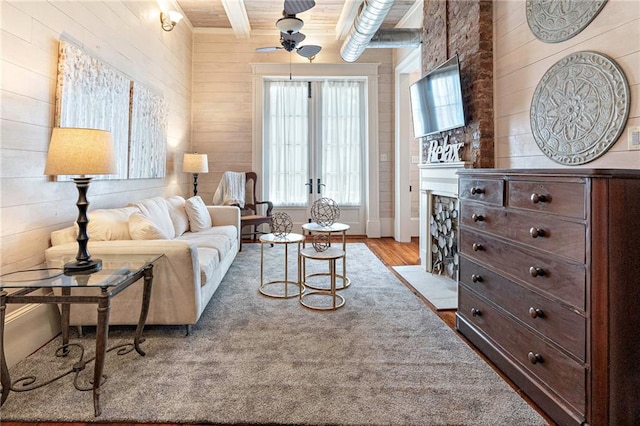 1244 Annunciation St, New Orleans, LA 70130 - living area with wooden walls, a fireplace with flush hearth, wood finished floors, a ceiling fan, and beam ceiling