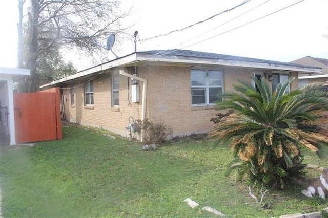 view of property exterior with brick siding and a lawn