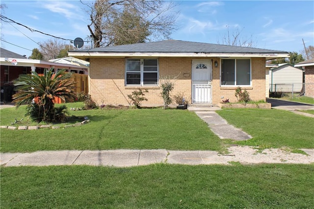 bungalow-style home featuring a front yard, brick siding, and fence