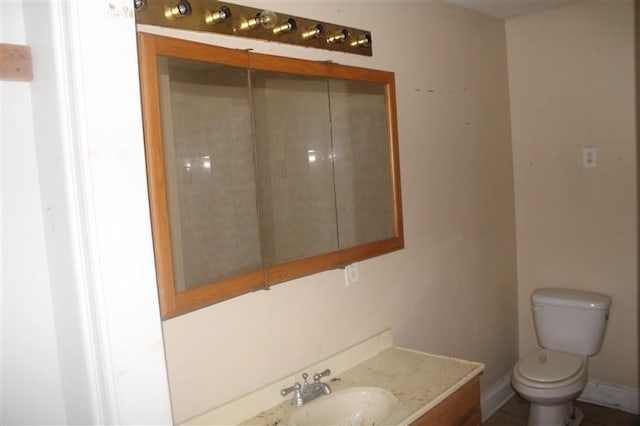 bathroom featuring toilet, baseboards, and vanity