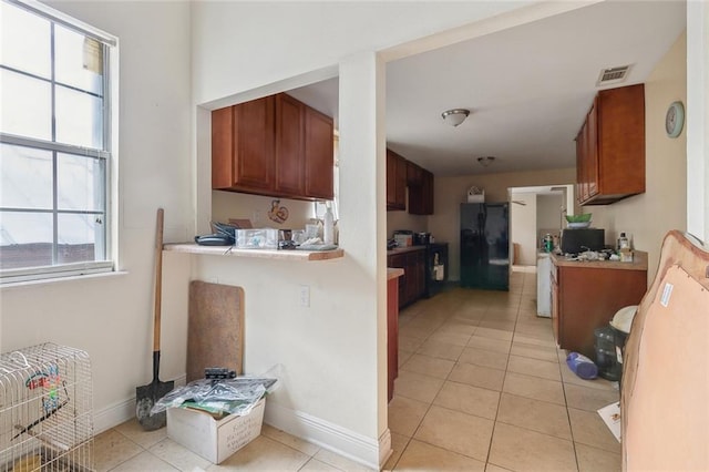 kitchen featuring light countertops, black fridge, light tile patterned flooring, and baseboards