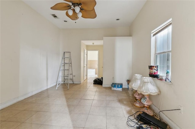 empty room with a ceiling fan, light tile patterned flooring, visible vents, and baseboards