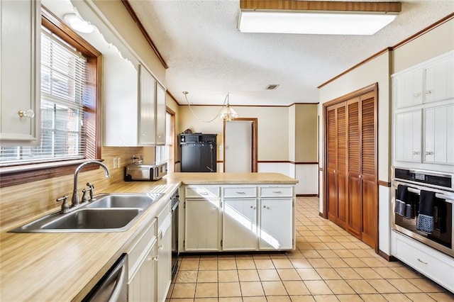 kitchen featuring a textured ceiling, oven, a peninsula, a sink, and light countertops